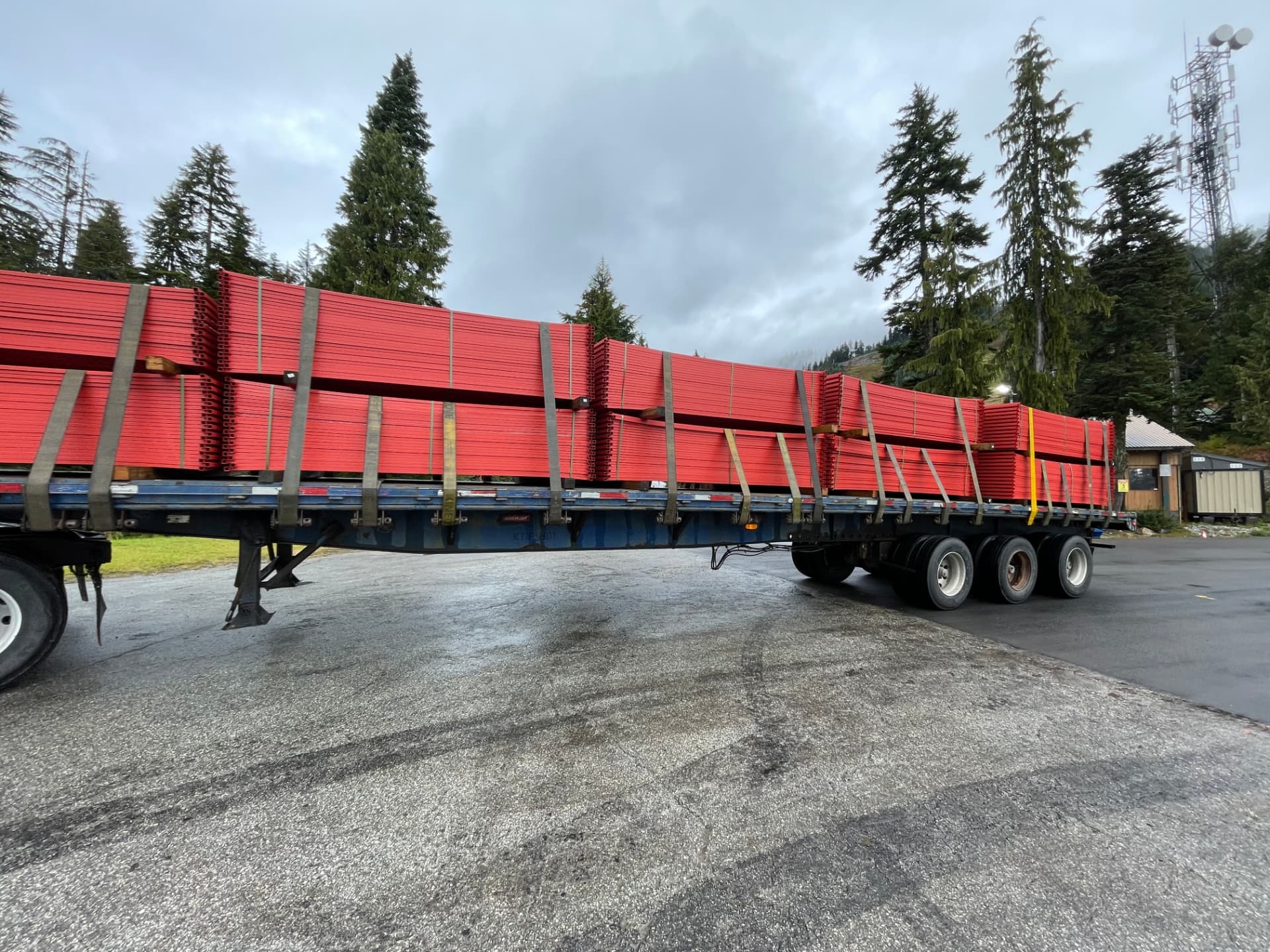 Flatbed trailer loaded with bundled red Clearline temporary fence panels