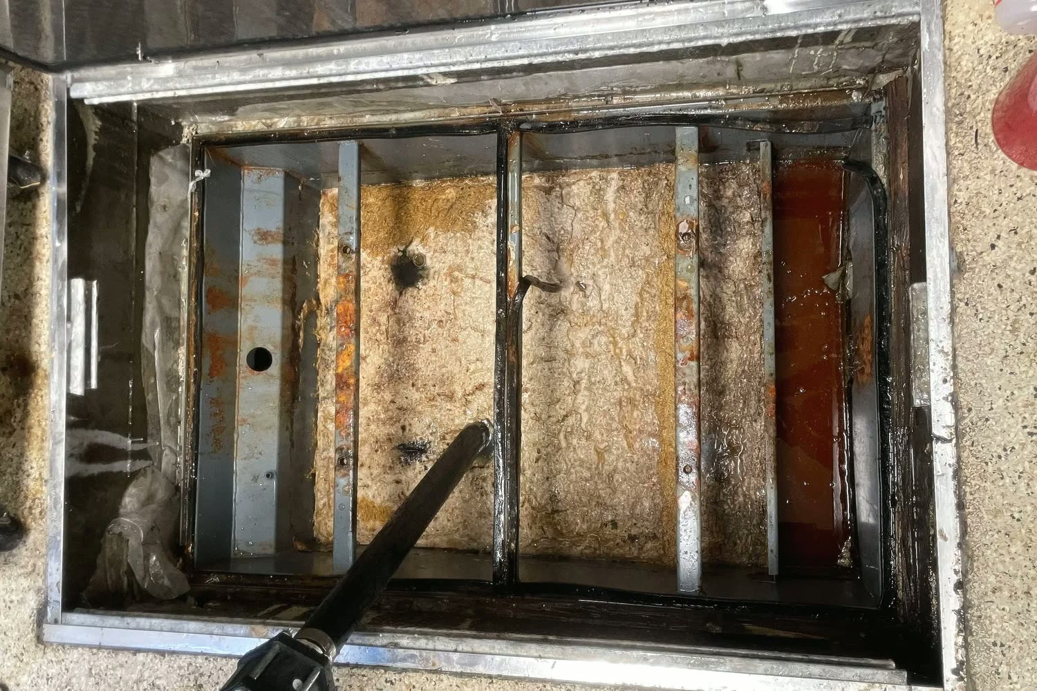 Grease trap with heavy black buildup before Clearline service